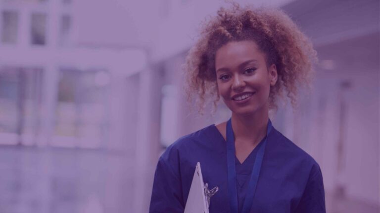 A female nurse, holding a clipboard and smiling